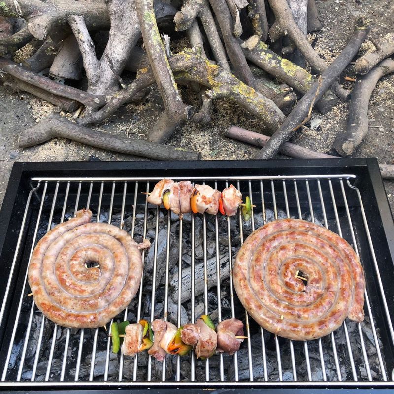 Due salsicce e due spiedini grigliati sul barbecue a carbone con girarrosto USB, realizzato da Allegri Girarrosti